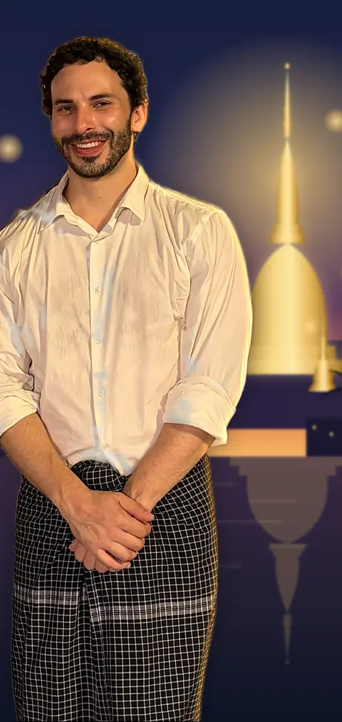 Sai Thura in a white dress shirt and a checked longyi